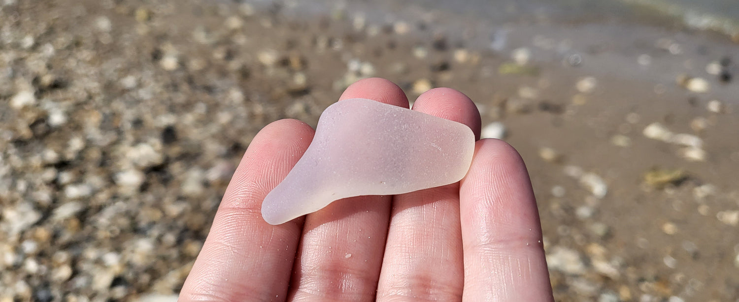 opalescent seaglass in palm of hand with sand and beach background