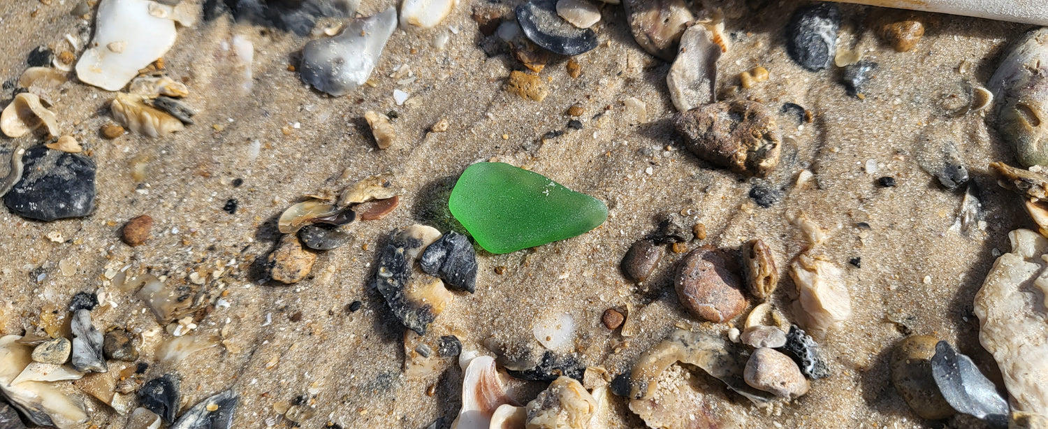 Small teardrop green seaglass on sand